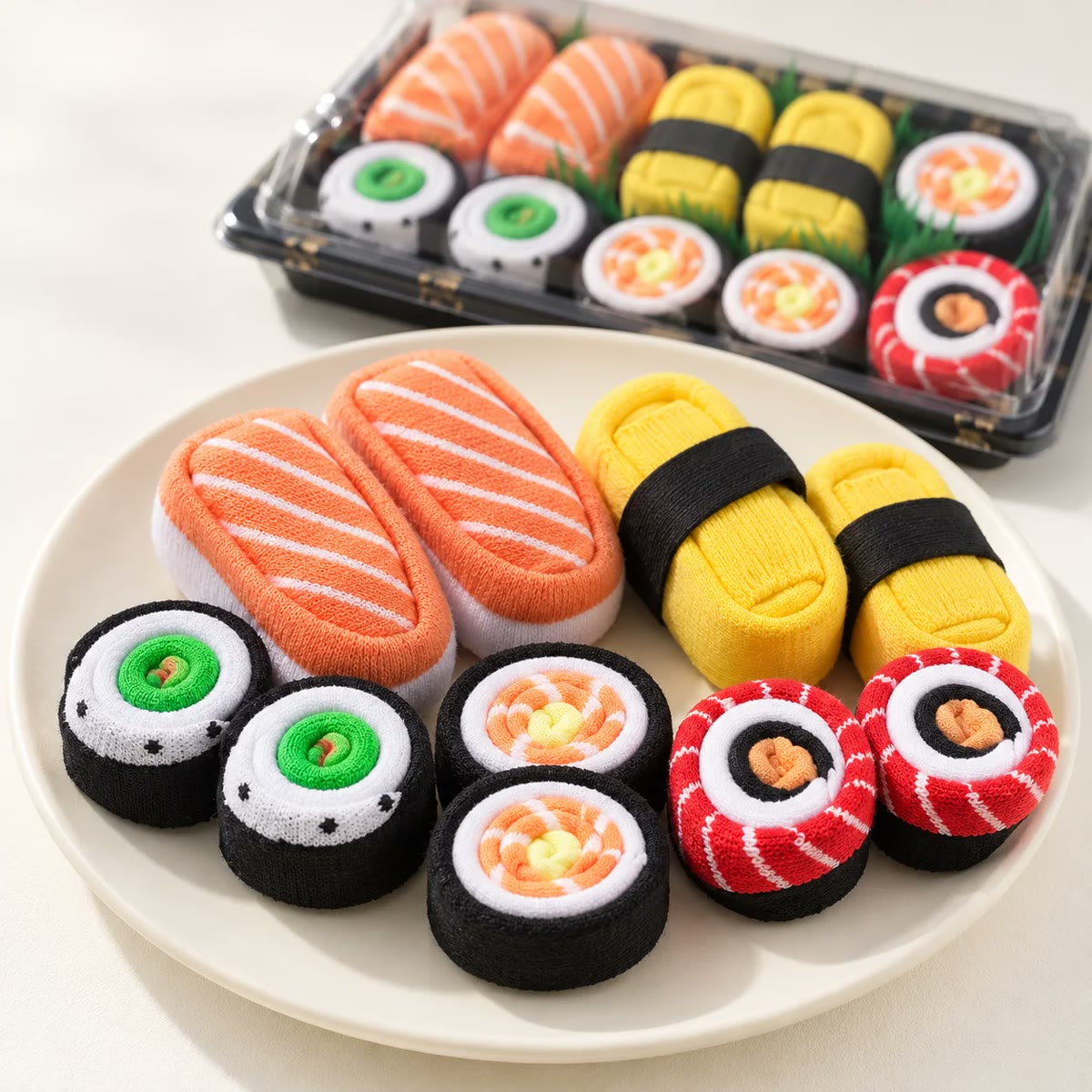Sushisokker rullet som maki og nigiri på et fat ved siden av esken